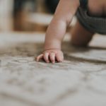 Ein Baby krabbelt auf einem Teppich