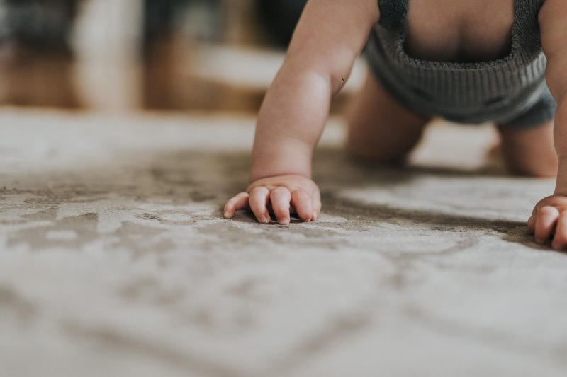 Ein Baby krabbelt auf einem Teppich