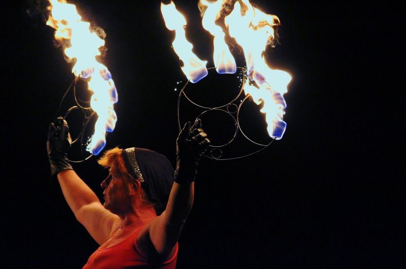 Eine Frau mit feuerfesten Handschuhen hält brennende Ringe