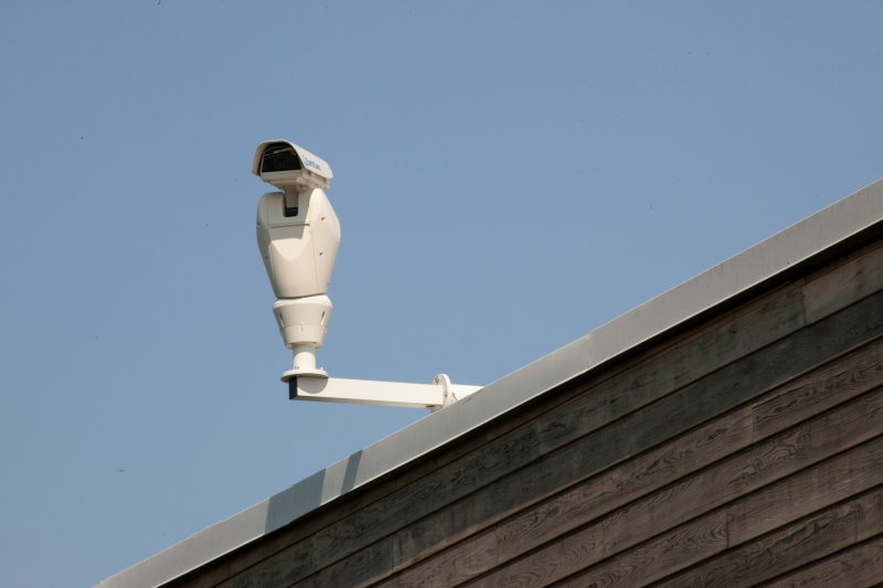 PTZ-Kamera auf einem Hausdach vor blauem Himmel